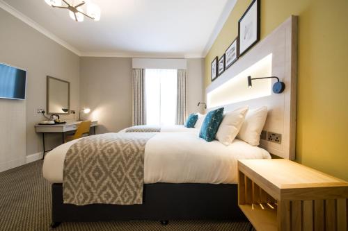 a hotel room with a large bed and a desk at The Dun Cow by Innkeeper's Collection in Rugby