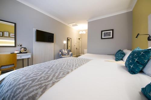 a bedroom with a large white bed with blue pillows at The Dun Cow by Innkeeper's Collection in Rugby