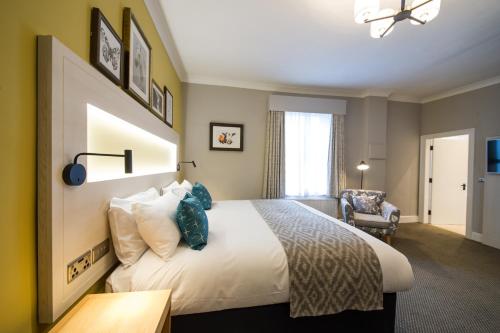 a hotel room with a bed and a chair at The Dun Cow by Innkeeper's Collection in Rugby