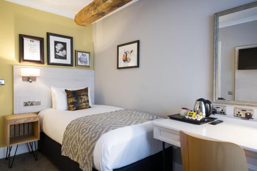 a hotel room with two beds and a desk at The Dun Cow by Innkeeper's Collection in Rugby