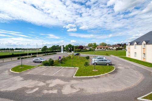 a parking lot with two cars parked in it at The Originals City, Hôtel Acadine, Le Neubourg in Le Neubourg