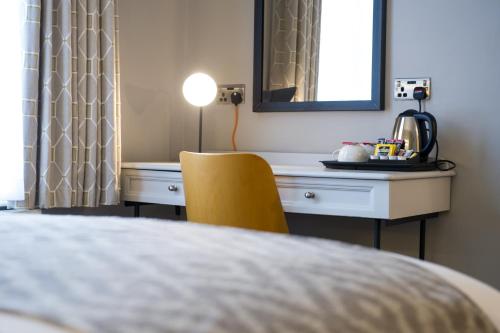 a bedroom with a desk and a yellow chair at The Dun Cow by Innkeeper's Collection in Rugby