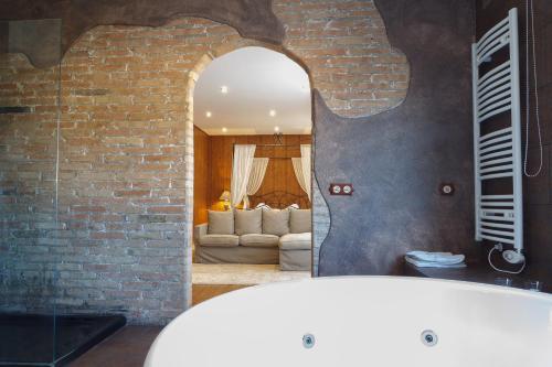 ein Badezimmer mit einer weißen Badewanne und einer Ziegelwand in der Unterkunft El Molí de Pontons suites con jacuzzi spa in Pontons