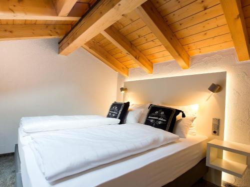 a bedroom with two white beds and wooden ceilings at Elements Hotel Christlessee in Oberstdorf