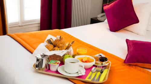 een dienblad met ontbijtproducten op een bed bij Hôtel du Plat d'Etain in Parijs