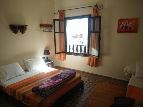 um quarto com uma cama e uma janela em Hotel Coeur de Mogador em Essaouira