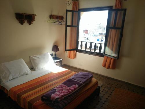 a bedroom with a bed and a large window at Hotel Coeur de Mogador in Essaouira