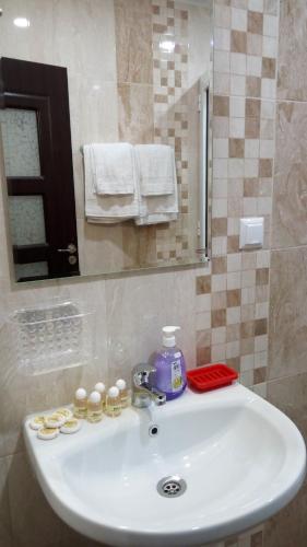 a bathroom sink with a bottle of soap and a mirror at White home-apartament in Burgas