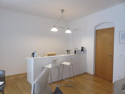 a living room with a bar with white stools at Historisches Bürgerhaus Dresden -Kulturstiftung- in Dresden