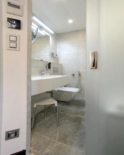 a white bathroom with a sink and a toilet at Hotel Grand in Český Krumlov