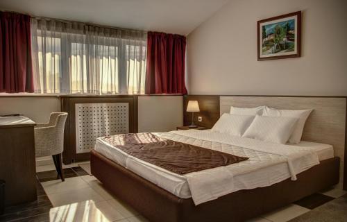 a bedroom with a bed and a desk and a window at Hotel Albo in Bor