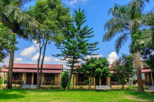 a building with palm trees in front of it at Tiger Residency Resort in Sauraha