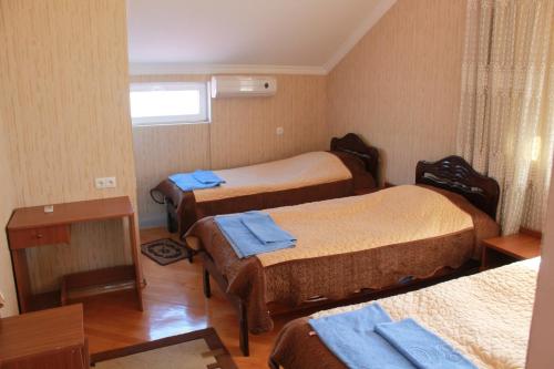 a room with three beds with blue towels on them at Nona Guest House in Shilda
