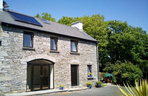 a stone house with solar panels on the roof at SunnySide-Cottage in Ennistymon