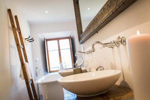 a bathroom with two sinks and a window and a candle at Hotel & Gourmetwirtshaus Kirchenwirt seit 1326 in Leogang