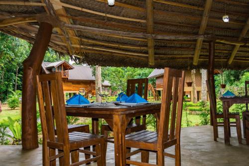 a wooden table and chairs under a wooden roof at Kandy Cabana in Kandy