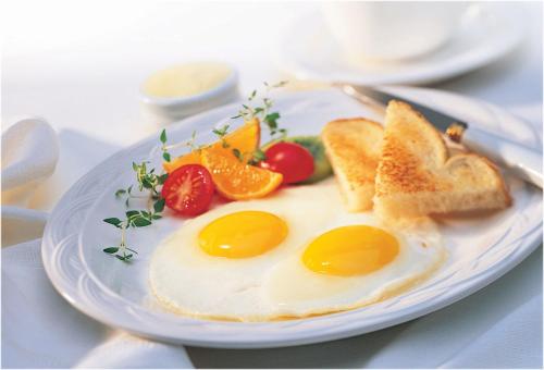 um prato de ovos e pão com torradas e tomates em Dalat Flowery hotel & coffee em Da Lat