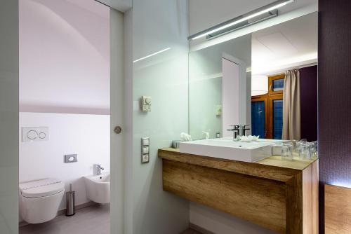 a bathroom with a sink and a toilet and a mirror at Karoly Corner Residences in Budapest