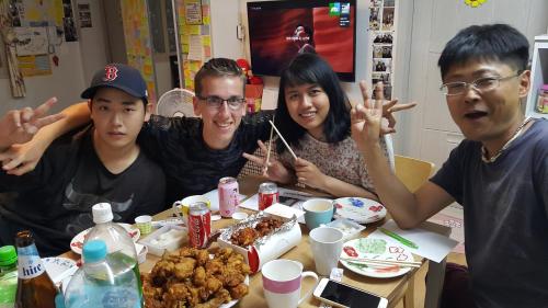a group of people sitting at a table with food at Panda Guesthouse in Gwangju