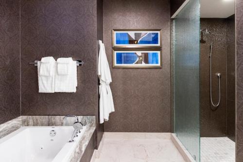 a bathroom with a tub and a glass shower at The Jung Hotel and Residences in New Orleans