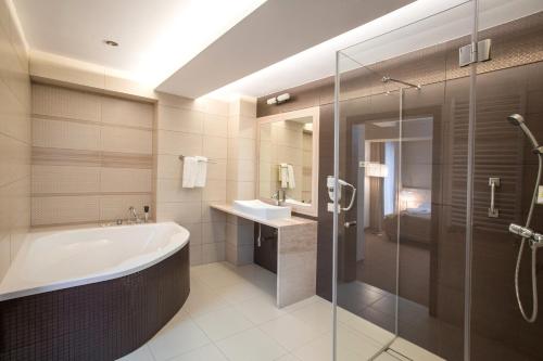 uma casa de banho com uma banheira e um chuveiro em vidro. em Hotel Zimowit em Rzeszów