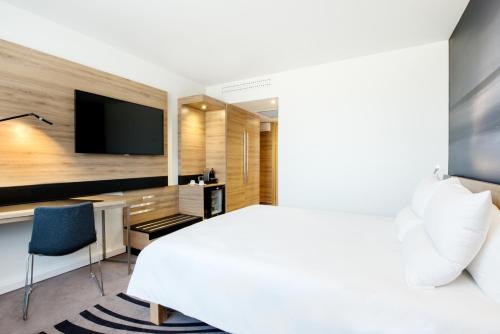 a hotel room with a bed and a desk and a tv at Novotel Warszawa Airport in Warsaw