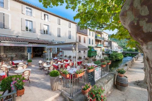 an outdoor restaurant with tables and chairs and a river at Hotel Restaurant des Maures in Collobrières