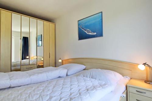 ヘルヌムにあるStrandmuschelのベッドルーム(大きな白いベッド1台、鏡付)