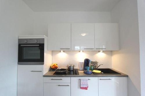 ヘルヌムにあるRobbeの白いキャビネットと黒い電子レンジ付きのキッチンが備わります。