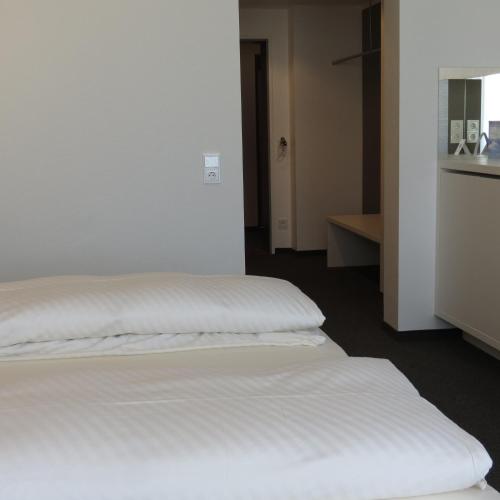 two beds in a room with white sheets at Comfor Hotel Ulm City in Ulm