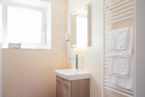 ein weißes Badezimmer mit einem Waschbecken und einem Spiegel in der Unterkunft Gasthof Martinhof in Sankt Martin im Sulmtal