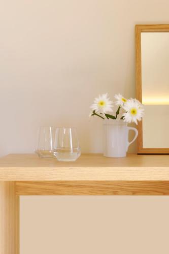 a table with two glasses and a vase with flowers at WeinKulturgut Longen-Schlöder in Longuich