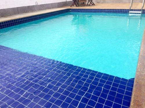 a swimming pool with blue tiles on the floor at Trevo De Arraial pousada em cabo frio in Cabo Frio