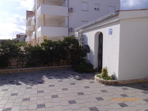 a building with a gate next to a courtyard at Apartments Lidija in Pag