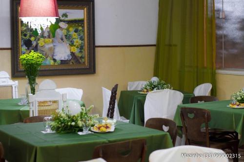 a dining room with green tables and white chairs at Aimores Palace Hotel in Aimorés