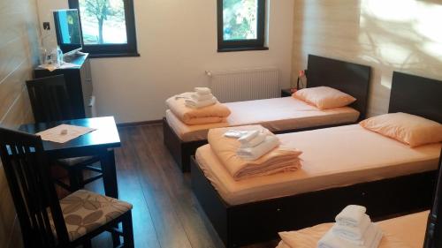 three beds in a room with a table and chairs at Complex Friends in Pleven