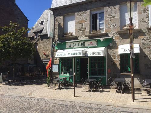 a building with tables and chairs in front of it at Le Grillon in Pontorson