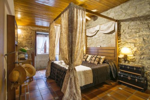 ein Schlafzimmer mit einem Himmelbett in einem Zimmer in der Unterkunft Aldea Os Muiños in As Mirans