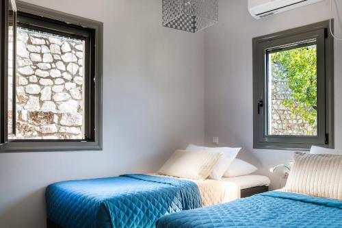 two beds in a room with two windows at Myrtos Bay Apartments in Anomeriá