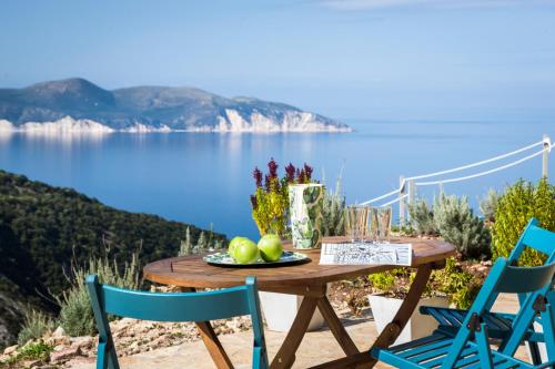 a wooden table with a plate of fruit and two chairs at Myrtos Bay Apartments in Anomeriá