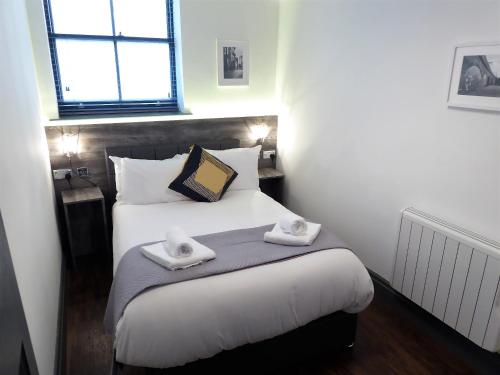 a bedroom with a bed with two towels on it at Stables at The Coach House Apartments in Leeds