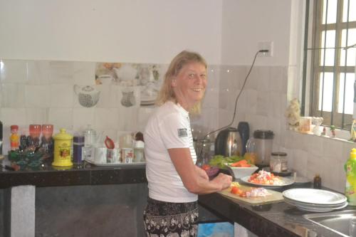 a woman standing in a kitchen preparing food at Kuma Beach side Villa in Wadduwa