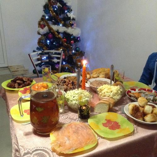 a table with a christmas meal with a christmas tree at Homestay Khomenko in Perechin