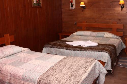two beds in a hotel room with towels on them at Hostal el Nogal Pucón in Pucón