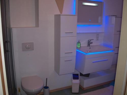 a bathroom with a toilet and a sink with blue lights at Appartement-im-Lebenstor-Angeln in Sterup