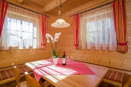 a wooden dining room with a table with a bottle of wine at Achenseer Hüttendörfl in Maurach