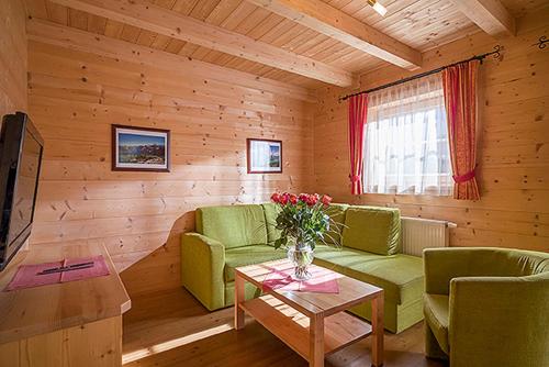a living room with green couches and a table with flowers at Achenseer Hüttendörfl in Maurach