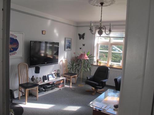 a living room with a flat screen tv and chairs at Guesthouse Sharon Aarhus in Aarhus