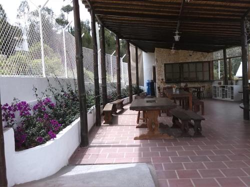 un patio con mesa, bancos y flores en San Benito Hotel, en Tibasosa