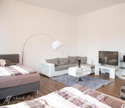 sala de estar blanca con sofá y TV en Smart and Happy Living Fürth, en Fürth